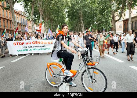 Ein junger Demonstrant auf einem Fahrrad vor der Prozession und dem Banner, stoppt den Völkermord an den Palästinensern, stoppt den Brand für immer. Demonstration gegen den Völkermord und für den Einzug humanitärer Hilfe in Gaza und für die Forderung nach einem Waffenstillstand und ein Ende der Straflosigkeit der israelischen Regierung. Frankreich, Toulouse, 14. Juni 2025. Foto: Patricia Huchot-Boissier/ABACAPRESS.COM Stockfoto