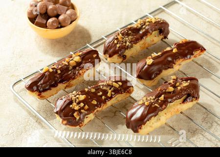 Erstklassiges Eclair-Dessert mit Milchschokolade und Nüssen, isoliert auf weißem Hintergrund. Stockfoto