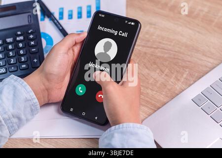 Die Hand einer Frau, die ein Smartphone hält und einen Anruf von einer unbekannten Nummer auf dem Bildschirm eingeht. Konzept für eingehende Spammer-Anrufe. Stockfoto