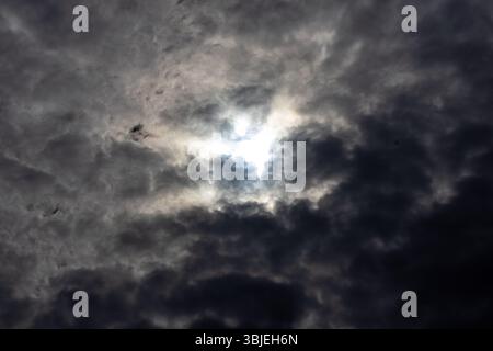 Dramatische dunkle Wolken sammeln sich vor Regen, und Sonnenstrahlen brechen durch. Unheilvolles stürmisches Wetter nähert sich. Stockfoto