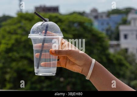 Transparente Einweg-Kunststoffbecher mit Innenhand, Kuppeldeckel und schwarzem Stroh. Ideal für Saft, kalte Getränke oder Getränke zum Mitnehmen. Stockfoto