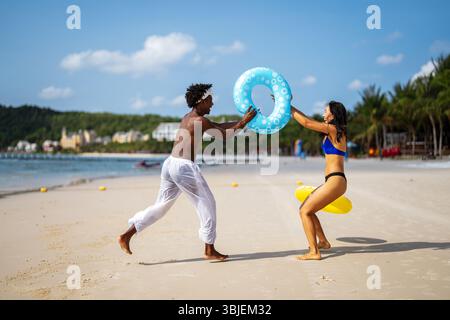 Interrassisches Paar, das einen romantischen Strandurlaub genießt und Liebe, Lachen und Zweisamkeit genießt Stockfoto