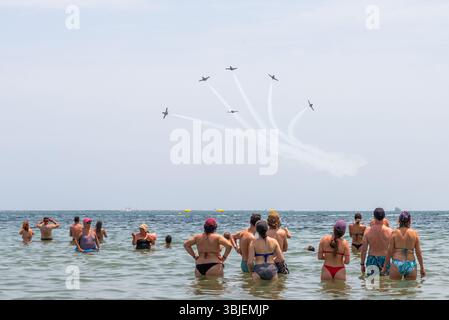 Santiago de La Ribera, San Javier, Spanien. Juni 2025. Das Kunstflugteam der spanischen Luft- und Raumfahrtstreitkräfte namens Patrulla Águila (Eagle Patrol) wurde am 4. Juli 1985 gegründet und feiert sein 40-jähriges Bestehen und das Ende seiner Zeit, als sie die Casa C-101 Aviojets auf Pilatus PC-21 Turboprop-Flugzeuge umsteigen. Die Jets, die über die Strände des Mar Menor zeigen, mit Menschen, die im Meer beobachten Stockfoto