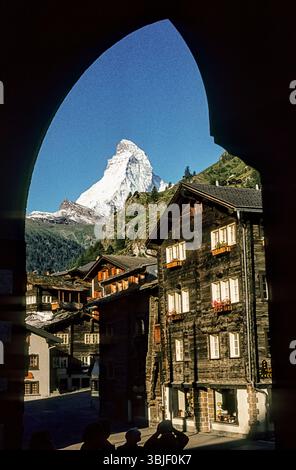 Dunkle Holzhäuser und das berühmte Matterhorn aus dem Dorf. Zermatt VS, Wallis, Schweiz, um 1982 Stockfoto