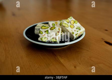 Pistazien mit Nougat, tolle Süßigkeiten. Auf einer schwarzen Porzellanplatte. Stockfoto