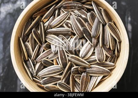 Gestreifte Sonnenblumenkerne in der Schüssel. Natürlicher rustikaler Snack. Veganes Bio-Essen. Gesunde pflanzliche Fette. Einfache trockene Zutat. Nahaufnahme Flachbild auf Marmor. Stockfoto
