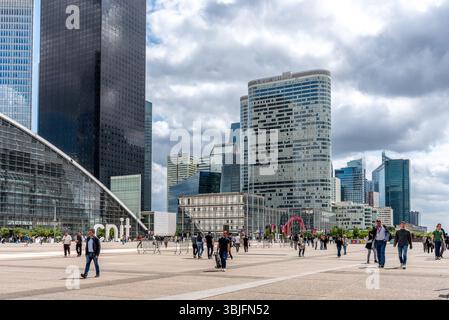 Menschen während der Mittagszeit im Geschäftsviertel La Défense mit Wolkenkratzern im Hintergrund. La Défense ist Europas größtes zweckgebautes Unternehmen Stockfoto