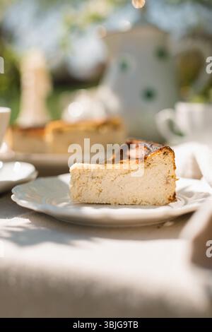Nahaufnahme eines Stücks baskischen Käsekuchen auf einem Gartentisch im Sommer für Nachmittagstee Stockfoto
