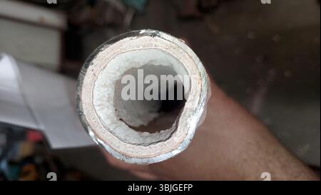 Bei der Nahaufnahme eines Rohrs wird eine erhebliche Kalksteinbildung im Inneren deutlich, was die Minerallagerstätten aus der langfristigen Nutzung in einer Werkstatt oder einer Tatsache zeigt Stockfoto