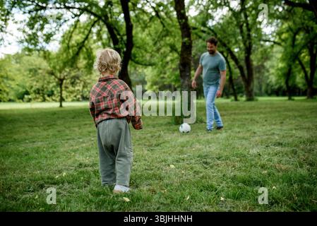 Vater und Sohn spielen zusammen Fußball im Park Stockfoto