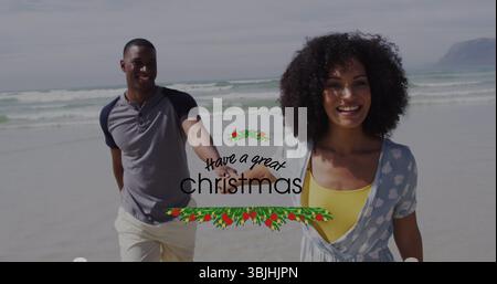 Spazierendes Paar, das Hände am Sandstrand unter bewölktem Himmel hält, mit Weihnachtsgrüßgrafik Stockfoto