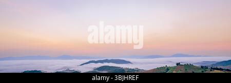 Atemberaubendes Bergpanorama mit dichtem weißen Nebel und Wolken bei Sonnenaufgang, sanften Pastellfarben, die eine friedliche natürliche Landschaft perfekt schaffen Stockfoto