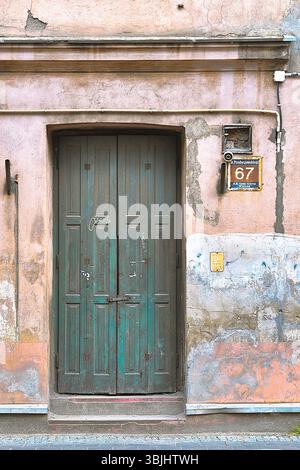 Alte grüne Tür an einer verwitterten, bemalten Wand Stockfoto