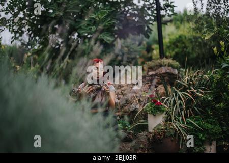 Mädchen, das friedlich eine große Schlange in einem üppigen Garten hält Stockfoto