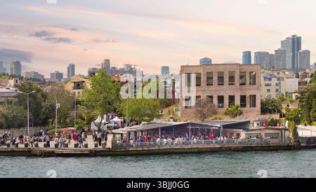 Istanbul, Türkei - 8. Mai 2023: Uferszene mit Menschen, die an einer Promenade speisen und spazieren gehen, mit alten und modernen Gebäuden in der Skyline der Stadt Stockfoto