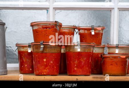 Eine Reihe von Gläsern gefüllt mit roter Sauce. Die Gläser sind übereinander gestapelt, was ein Gefühl von Fülle und Abwechslung schafft. Die Szene vermittelt ein f Stockfoto