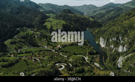 Malerisches ländliches Tal mit verwinkelten Straßen, verstreuten Häusern und einem Fluss am Berg im Tara Nationalpark. Serbien im Frühling. Stockfoto