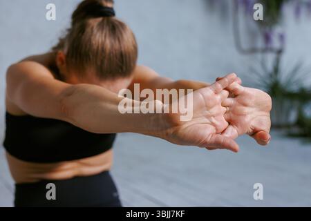 Nahaufnahme einer Frau, die die Arme in der Yoga-Praxis nach vorne streckt und dabei Flexibilität, Konzentration und achtsame Bewegung hervorhebt. Stockfoto