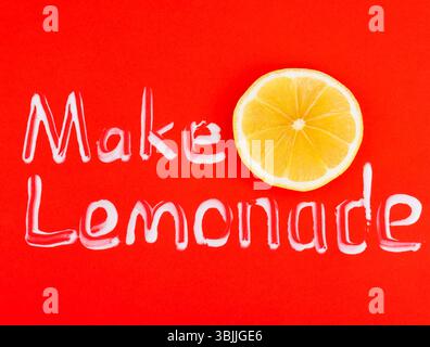Text als Limonade auf rotem Hintergrund mit einer Scheibe Zitrone machen Stockfoto