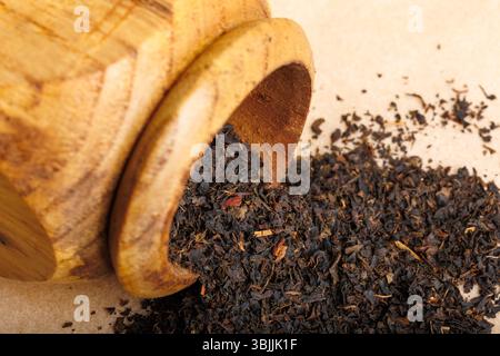 Trockene schwarze Teeblätter in Holzmörtel Stockfoto