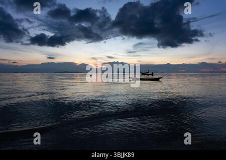 Dämmerung über einem ruhigen Meer mit Silhouetten Fischerbooten Stockfoto