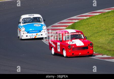 Zwei Trabant-Rennwagen, die nebeneinander auf der Rennstrecke von Autodrom Most, Tschechien, antreten. Historische Fahrzeuge bei einem Oldtimer-Motorsport-Event. Stockfoto