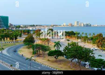 Blick auf eine Straße, Yachtclub und Ilha de Luanda bei Sonnenuntergang. Luanda, Angola Stockfoto