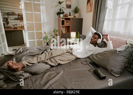 Entspannender junger Mann, der Musik mit Kopfhörern hört Stockfoto