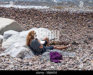Juni 2025. Sidmouth, Devon Zeit zum Entspannen und Lesen eines Buches, während Sie das herrliche Wetter im Juni an der Devon Küste in Sidmouth genießen. Photo Central/Alamy Live News Stockfoto