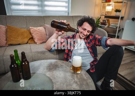 Ein Mann, der zu Hause Bier ins Glas gießt Stockfoto
