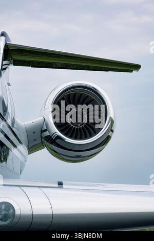 Jet-Triebwerk und T-Heck eines Luxus-Gulfstream-Geschäftsjets unter teilweise bewölktem Himmel. Polierte Rumpf- und Turbinendetails sind deutlich sichtbar. Stockfoto