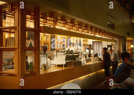 Ubud, Bali, Indonesien – 13. Mai 2025: Moderne Coffee Bar mit moderner Espresso-Maschine und Baristas in warmer Holzeinrichtung Stockfoto