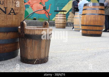 09.3.2025 Moldawien Ein rustikaler Holzeimer und Vintage-Fässer neben einer wunderschönen farbenfrohen Wandmalerei Stockfoto