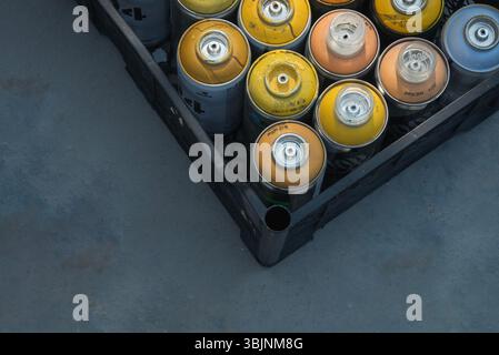 Graffiti-Spraydosen in Kiste auf blauem Betonboden. Abstraktes Dreieck. Stockfoto