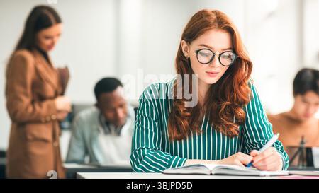 Studentin sitzt am Schreibtisch in Klassenzimmer Schreibprüfung Stockfoto