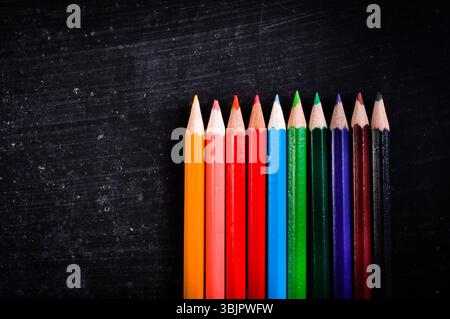 Bunte Bleistifte gegen schwarze Tafel Stockfoto