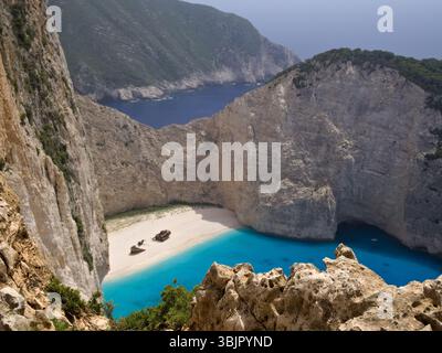 Luftbild des Navagio Beach auf der Insel Zante mit dem berühmten Schiffswrack, eingerahmt von Steinen und Büschen, türkisfarbenem Meer und Klippen im Blick. Stockfoto