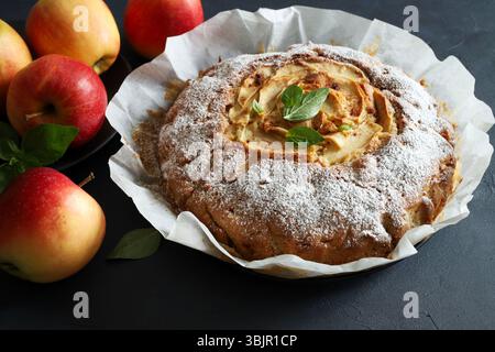 Weicher und köstlicher hausgemachter Apfelkuchen, frische Äpfel auf grauem Hintergrund. Direkt darüber. Stockfoto