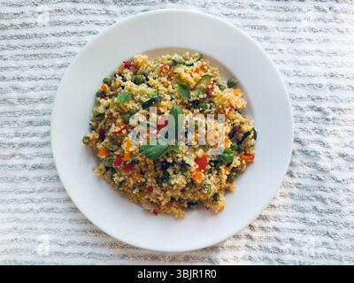 Couscous mit gekochtem Gemüse wie Karotten, Zucchini, Paprika und frischem Basilikum. Veganer Salat. Gesunde und vegetarische Lebensmittel. Direkt darüber. Stockfoto