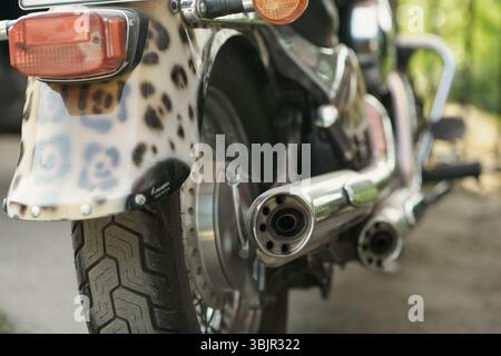 Das Heck des individuell gestalteten Motorrads zeigt Kotflügel mit Leopardenmuster, zwei Chrom-Auspuffschalldämpfer und eine robuste Hinterradlauffläche mit Rücklicht und Blinker Stockfoto