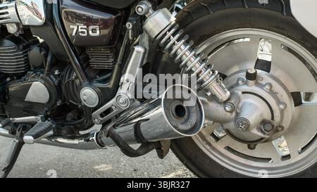 Vintage-Motorradseite mit Chrom-Auspuffschalldämpfer, Schraubenfeder-Stoßdämpfer, 750 Seitenverkleidung und Hinterrad bei Tageslicht, poliertem m Stockfoto