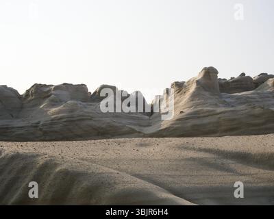 Weiße vulkanische Felsformationen am Sarakiniko Beach auf der Insel Milos, gefangen in warmgelbem Morgenlicht mit abstrakter Textur. Stockfoto