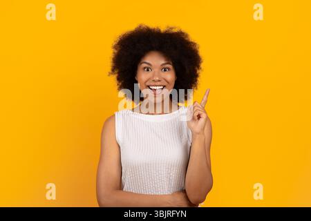Ideenkonzept. Aufgeregte junge schwarze Frau, die ihren Finger nach oben hebt Stockfoto
