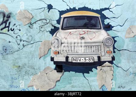 Realistische Darstellung eines Trabanten, der die Berliner Mauer durchbricht. Dramatisch und dynamisch, Graffiti an der Berliner Mauer in der East Side Gallery, Berlin Stockfoto