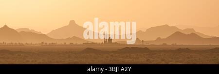 Silhouette einer Moschee bei Sonnenuntergang in Zentral-Iran, mit mehrschichtigen Hügeln, die unter warmem Licht in einer ruhigen Wüstenlandschaft in die Ferne fallen. Stockfoto
