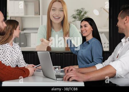 Gruppe von Personen, die an einer Geschäftskonferenz im Innenbereich teilnehmen. Lautsprecher auf Projektionsleinwand Stockfoto