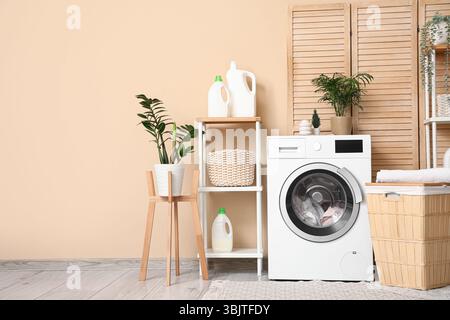 Stilvoller Waschraum mit moderner Waschmaschine, Korb, Regalfach und Waschmittelflaschen Stockfoto