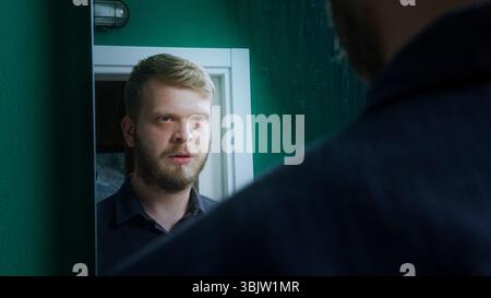 Ein bärtiger Mann steht drinnen und steht einem Polizisten mit einem ernsten Ausdruck gegenüber, was auf ein angespanntes oder wichtiges Gespräch hindeutet. Stockfoto