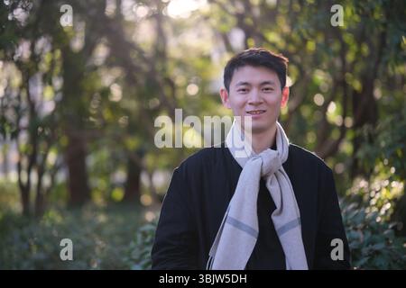 Porträt eines asiatischen jungen Mannes, der im Winter draußen lächelt Stockfoto