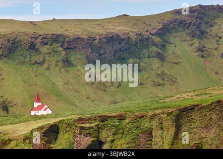 Malerische Kapelle mit rotem Dach in Vik. Felsige Landschaft. Island Stockfoto